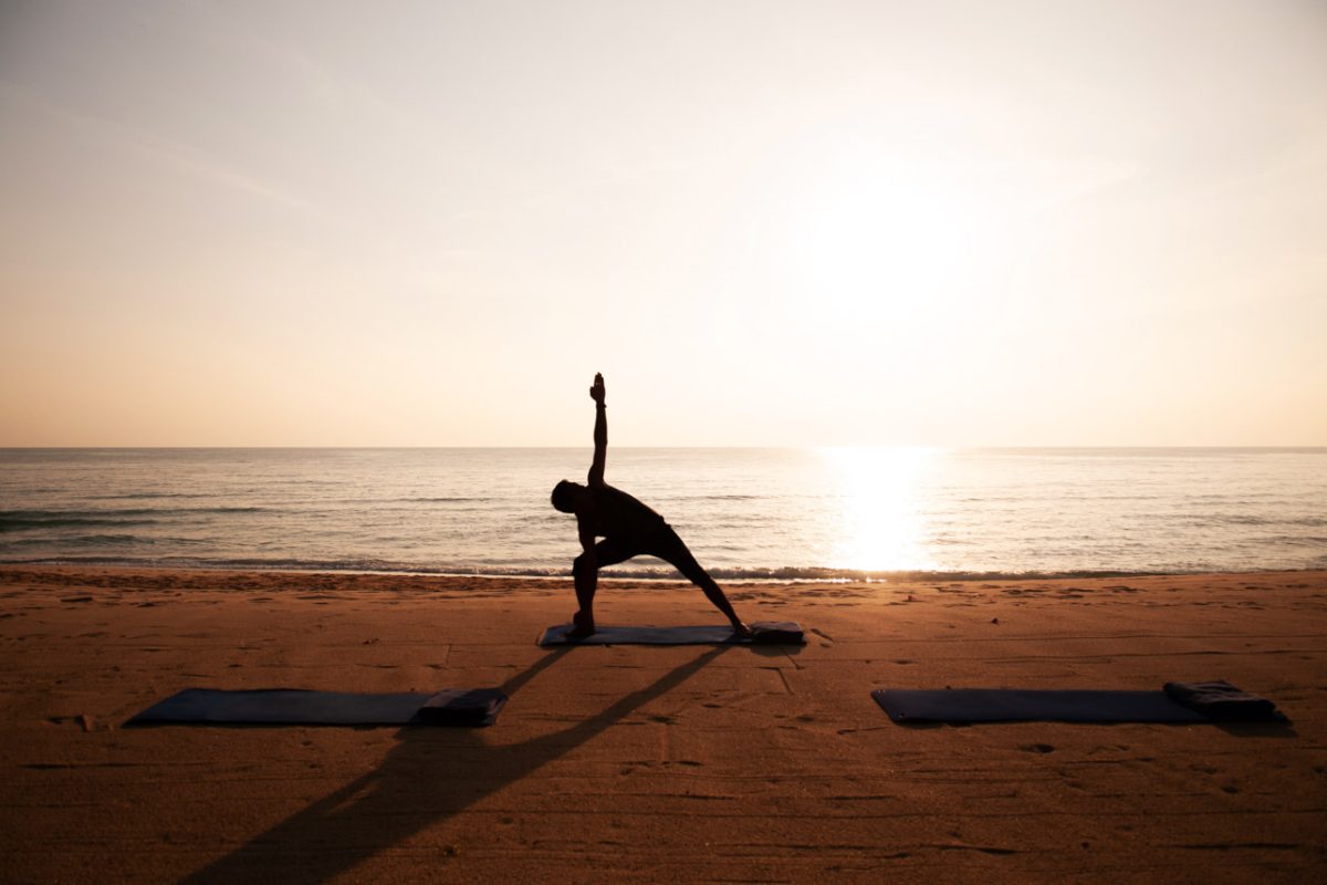 Silhouette Morning Yoga against rising sun on island beach