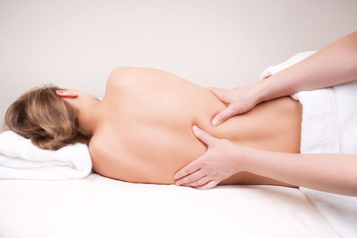 Deep tissue massage on the woman's middle back on erector spinae muscles