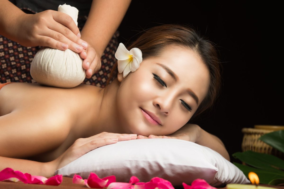 Asian woman getting thai herbal compress massage in spa.She is very relaxed