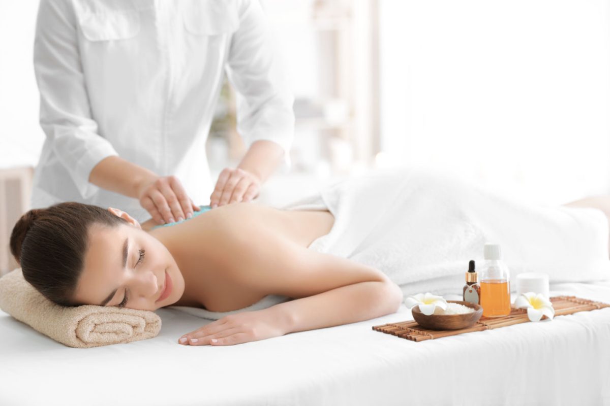 Beautiful young woman receiving scrub massage in spa salon